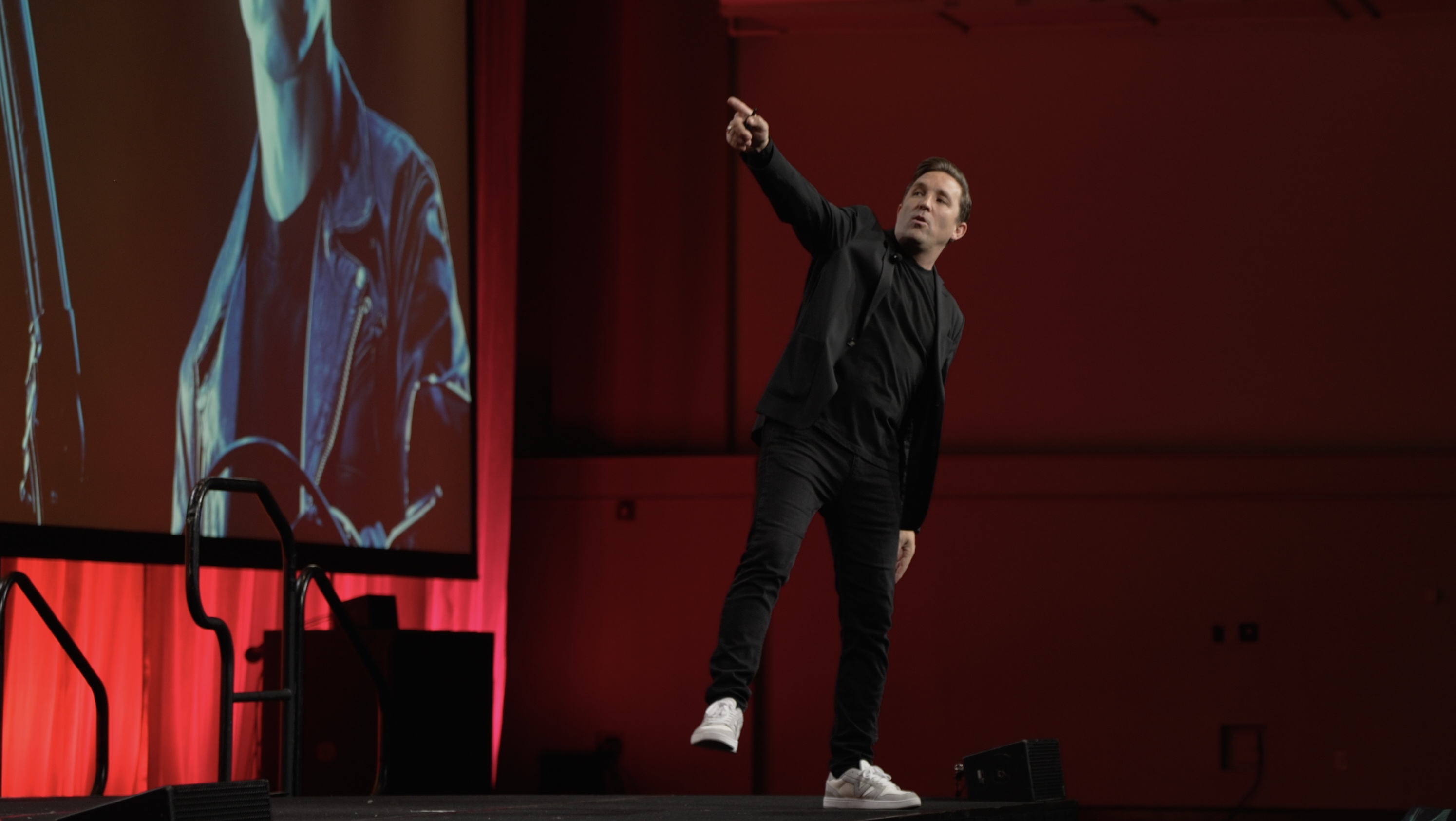 Frankie Russo pointing toward the audience on a red-lit stage